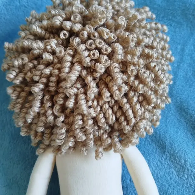 Cabelo de boneca feito de dezenas de cachinhos de lã costurados um a um